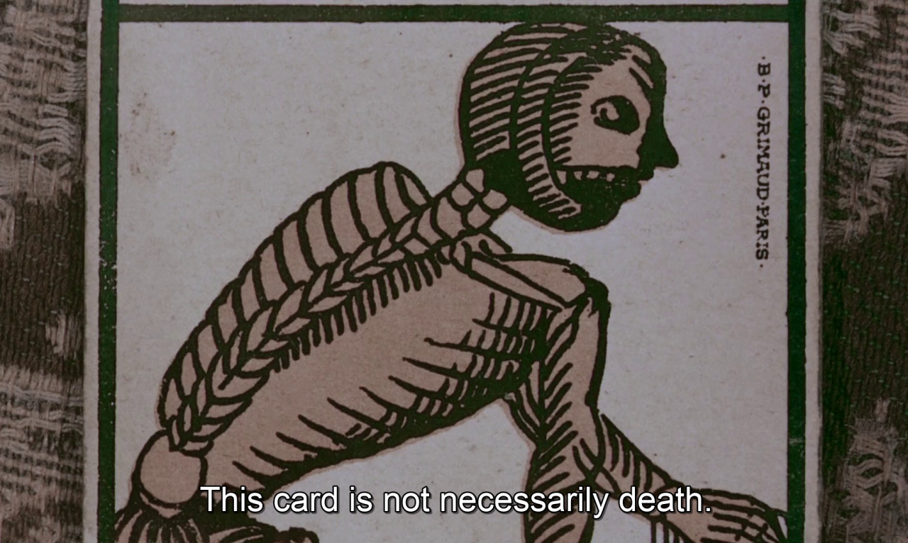 Film still showing the top half of the Death tarot card with white subtitles that read 'This card is not necessarily death.'